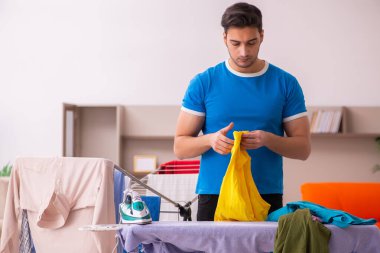 Genç adam evde ütü yapıyor.