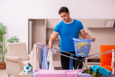 Genç adam evde ütü yapıyor.