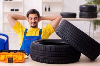 Atölyede lastiği olan genç bir erkek tamirci.