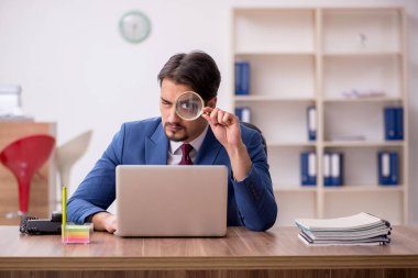 Genç erkek çalışan işyerinde oturuyor.