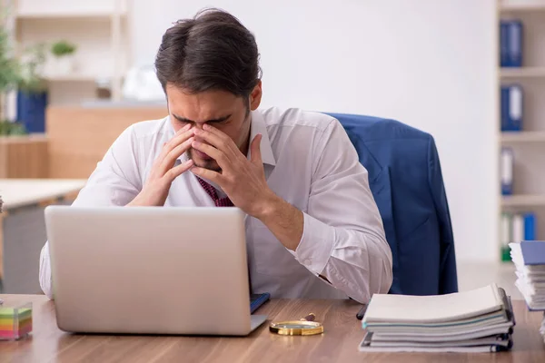 Young male employee and too much work in the office — Stock Photo, Image