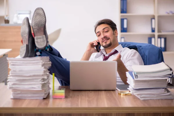 Young male employee and too much work in the office — Stock Photo, Image