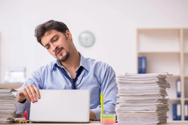 Joven empleado masculino y demasiado trabajo en la oficina —  Fotos de Stock