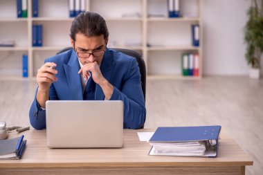 Genç erkek çalışan ofiste oturuyor.