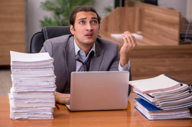 Genç bir erkek çalışan ve ofiste çok fazla iş var.