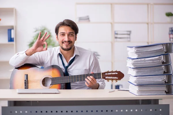 Jeune employé masculin jouant de la guitare sur le lieu de travail — Photo
