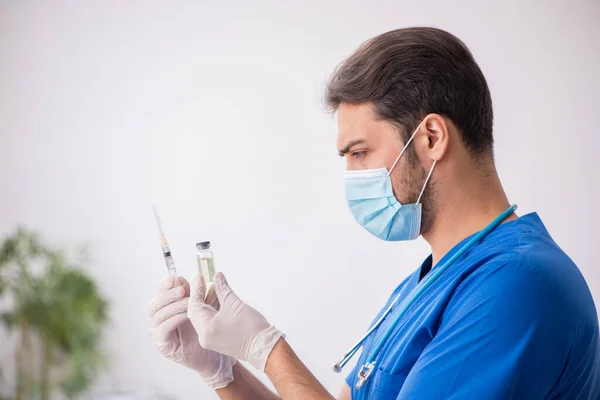 Joven médico en concepto de vacunación durante la pandemia —  Fotos de Stock