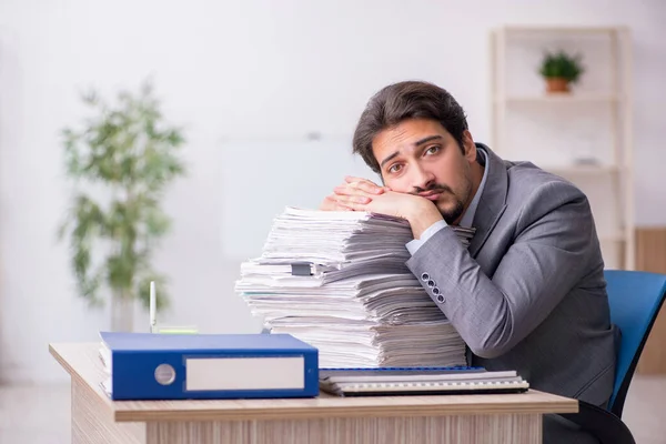 Ung manlig anställd och för mycket arbete på kontoret — Stockfoto