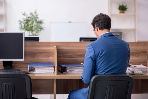 Empleado joven sentado en el lugar de trabajo — Foto de Stock