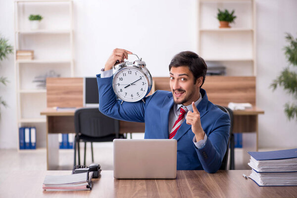 Young male employee in time management concept at workplace
