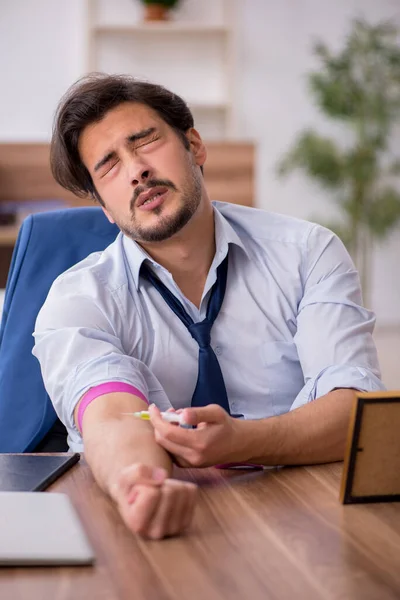 Joven hombre drogadicto empleado en el lugar de trabajo — Foto de Stock