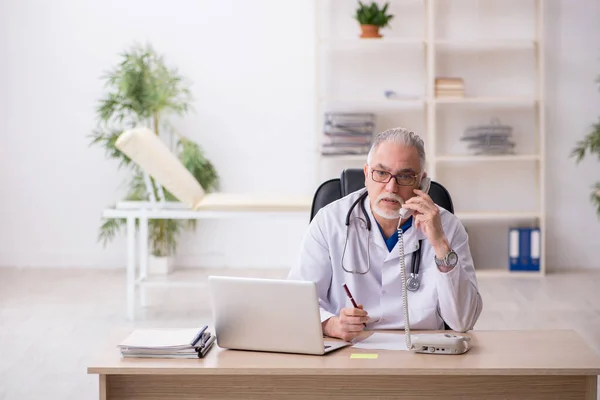 Klinikte çalışan yaşlı erkek doktor. — Stok fotoğraf