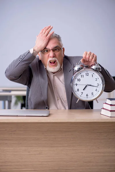 Old male teacher in front of whiteboard in time management conce