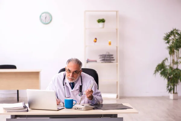 Klinikte çalışan yaşlı erkek doktor. — Stok fotoğraf