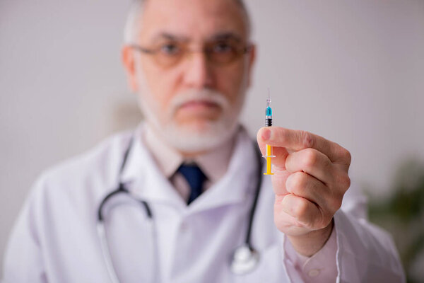 Old male doctor in vaccination concept