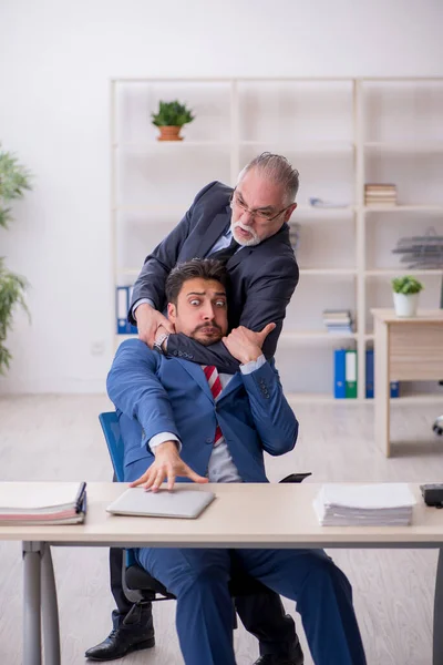 Velho chefe e jovem empregado masculino no conceito de bullying — Fotografia de Stock