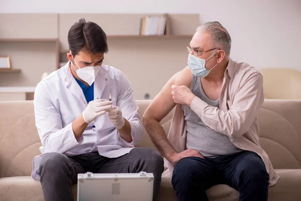 Giovane medico di sesso maschile visita vecchio paziente nel concetto di vaccinazione — Foto Stock