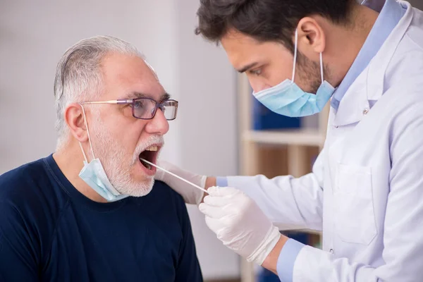 Paciente masculino de edad que visita al joven médico otorrinolaringologis — Foto de Stock