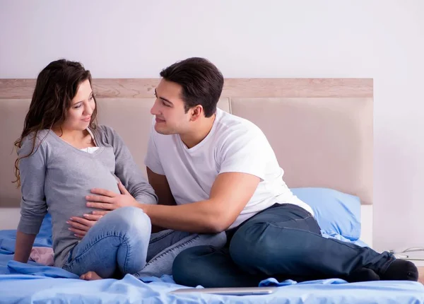 Mladá rodina s těhotnou ženou očekává dítě v posteli — Stock fotografie