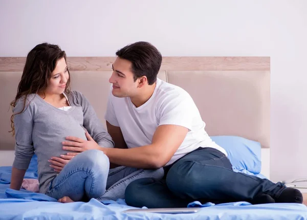 Familia joven con esposa embarazada esperando al bebé en la cama —  Fotos de Stock