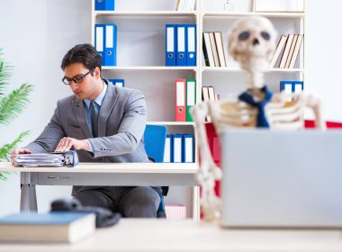 İskeletle çalışan bir iş adamı.