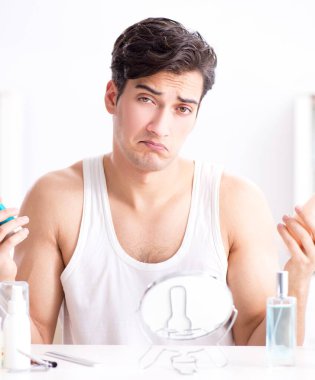 Genç yakışıklı adam aynaya bakıyor.
