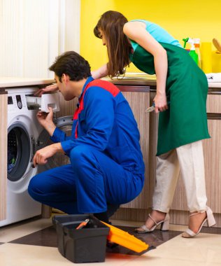 Müteahhit evde çamaşır makinesini tamir ediyor.