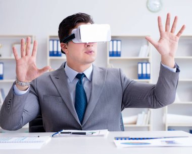 Ofiste sanal gerçeklik gözlüklü bir iş adamı var.