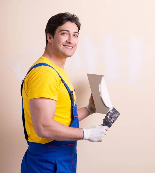 Молодой подрядчик наносит штукатурку на стену — стоковое фото
