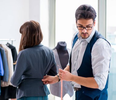 Profesyonel terzi resmi kıyafet için ölçü alıyor.