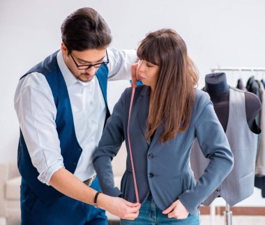 Profesyonel terzi resmi kıyafet için ölçü alıyor.