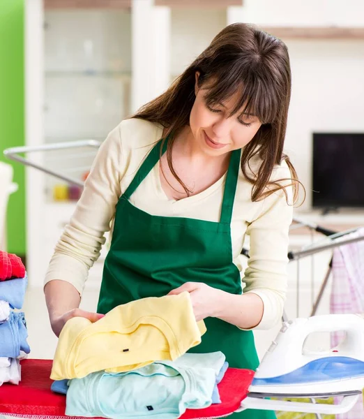 Mujer joven planchando ropa en casa — Foto de Stock