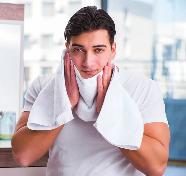 Genç yakışıklı adam yüz kremi sürüyor.