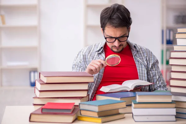 Jovem estudante do sexo masculino e muitos livros em sala de aula — Fotografia de Stock