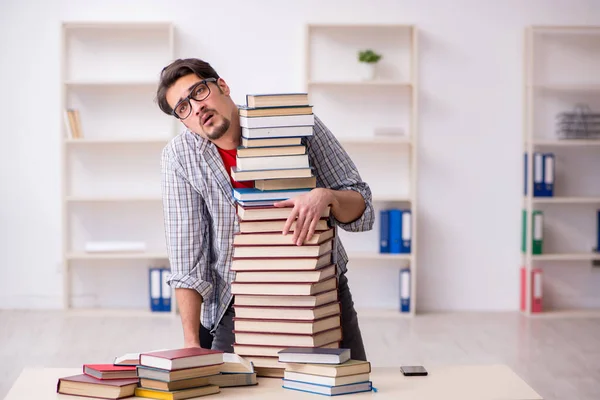 Giovane studente maschio e troppi libri in classe — Foto Stock