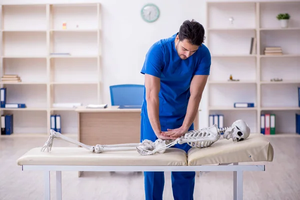 Jeune homme médecin examinant le squelette patient — Photo