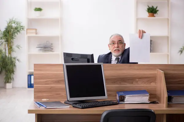 Trabalhador idoso sentado no local de trabalho — Fotografia de Stock