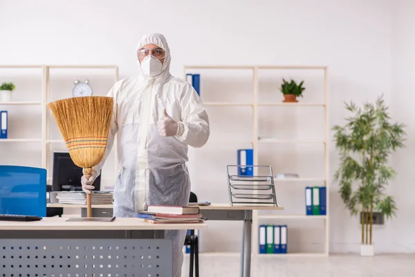 Oude mannelijke aannemer schoonmaken van het kantoor met bezem — Stockfoto