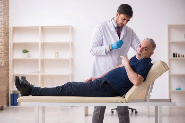 Old male patient visiting young male doctor in vaccination conce — Stock Photo, Image