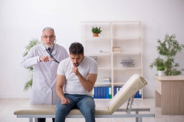 Genç erkek hasta yaşlı erkek doktoru ziyaret ediyor.