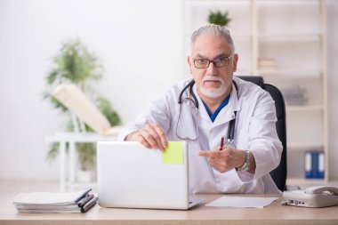 Klinikte çalışan yaşlı erkek doktor.