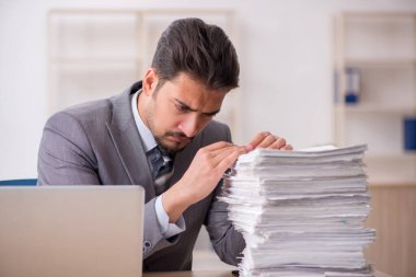 Ofisteki aşırı işten memnun olmayan genç bir erkek işçi.