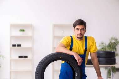 Atölyede lastiği olan genç bir erkek tamirci.