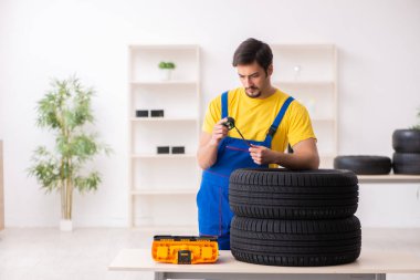 Atölyede lastiği olan genç bir erkek tamirci.