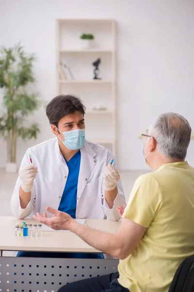 Yaşlı erkek hasta aşılama bölümünde genç bir erkek doktor. — Stok fotoğraf