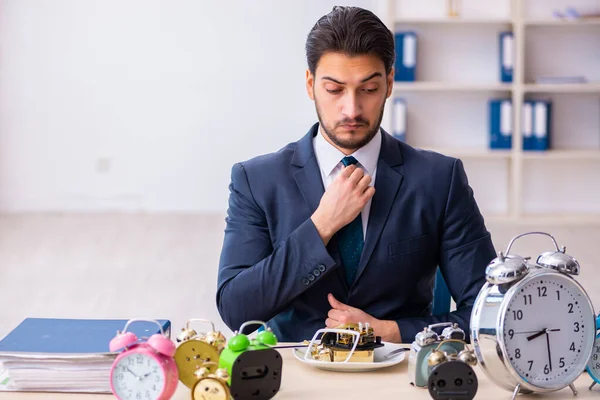 Joven empleado de negocios comiendo despertador-reloj —  Fotos de Stock