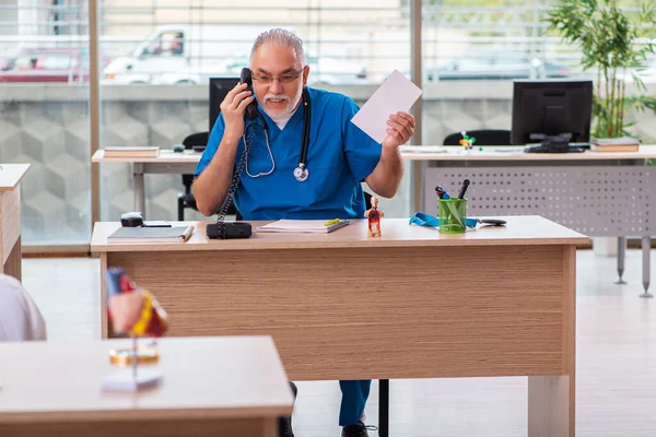 Gammal manlig läkare som arbetar på kliniken i telemedicin koncept — Stockfoto