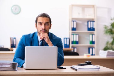 Genç bir erkek işçi ve ofiste çok fazla iş var.