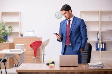 Genç erkek çalışan işyerinde oturuyor.