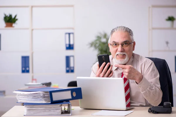 Homem velho empregado sentado no local de trabalho — Fotografia de Stock